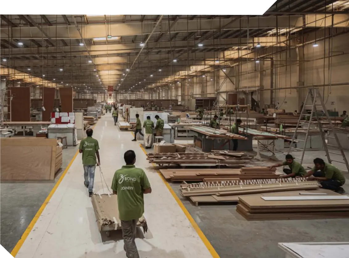 Workers in green Bond Joinery shirts among timber panels and workbenches in a large factory hall